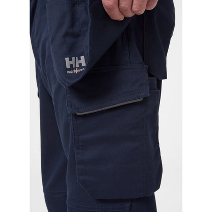 Bližnji posnetek funkcionalnih visečih žepov z dvojnim dnom za vijake in orodje na modrih hlačah Helly Hansen