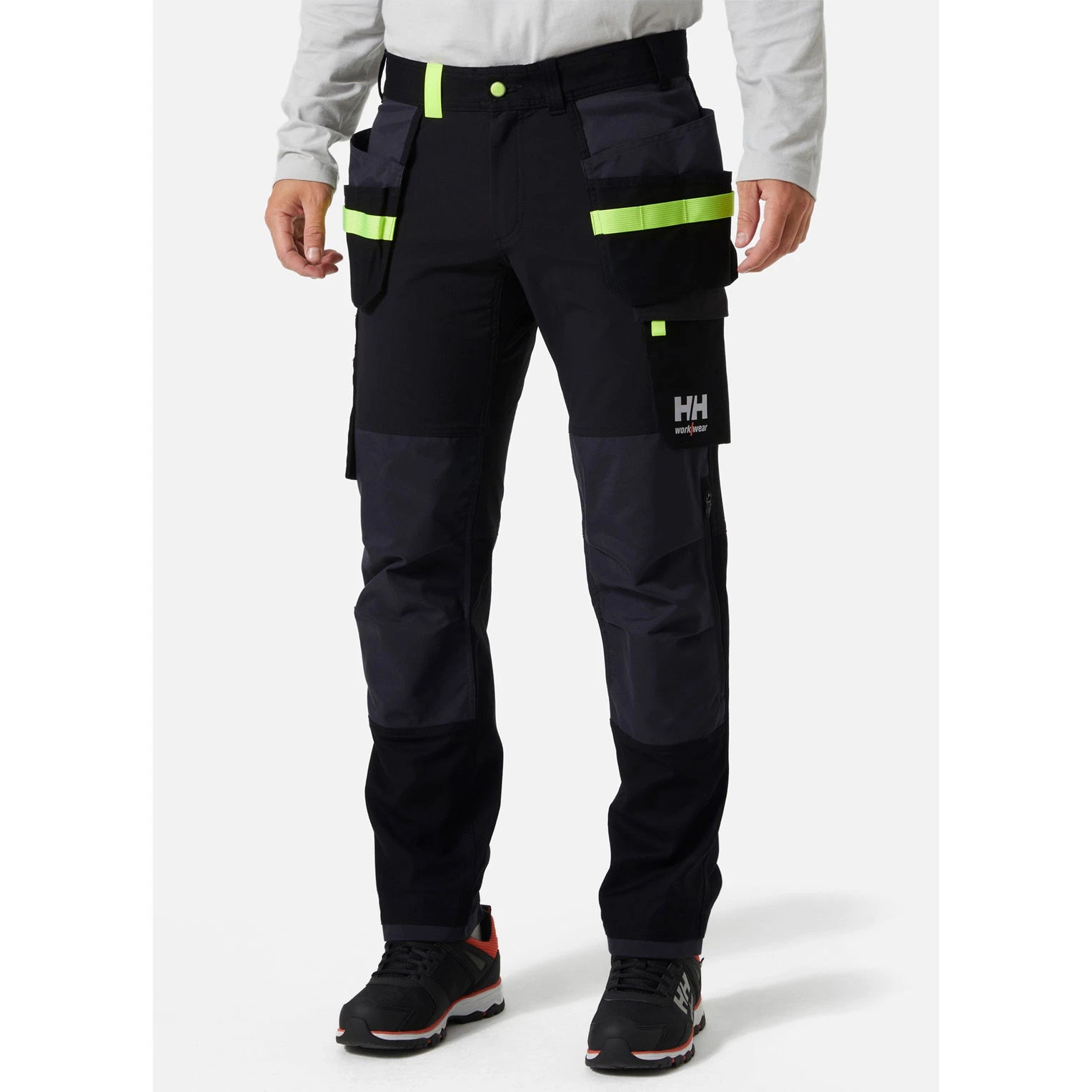 Obrtnik pri delu uporablja premium črne raztegljive delovne hlače Helly Hansen Oxford Construction s 4-way stretch prožnostjo